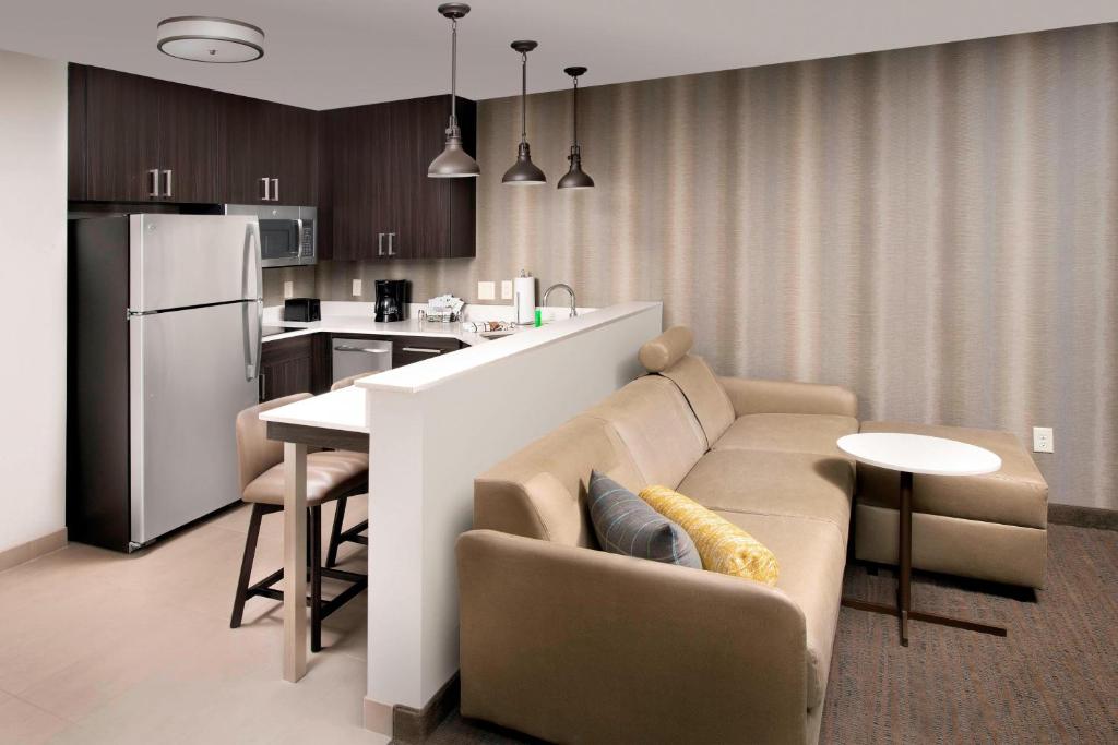 亚瑟港Residence Inn By Marriott Port Arthur的厨房以及带沙发和桌子的客厅。