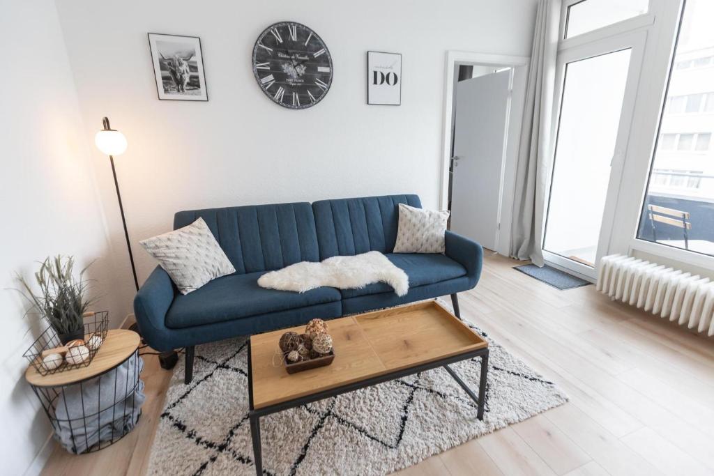 不来梅港Koje Sieben I Apartment im Zentrum mit Meerblick的客厅配有蓝色的沙发和桌子