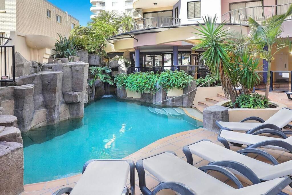 穆卢拉巴2 Bedroom Central Mooloolaba Resort with Pool, Spa, Mini Golf的一座大楼前带椅子的游泳池