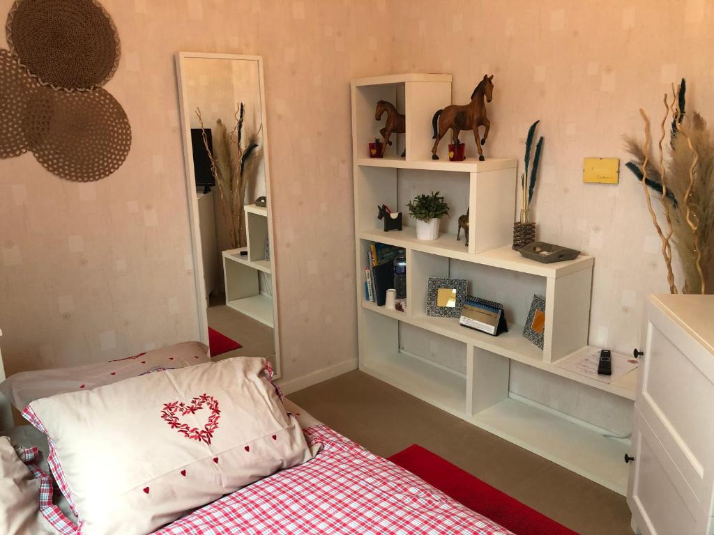 滨海埃尔芒维尔Coquelicot的卧室配有一张床和架子,墙上挂着马