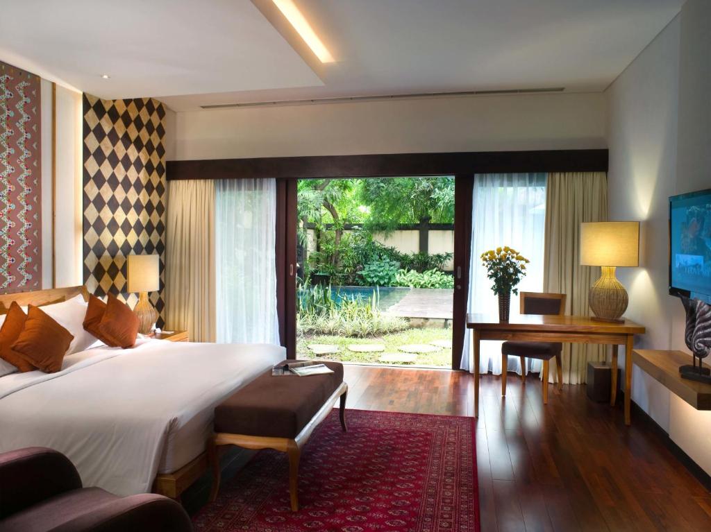 库塔登巴厘别墅的一间卧室配有一张床、一张书桌和一个大窗户