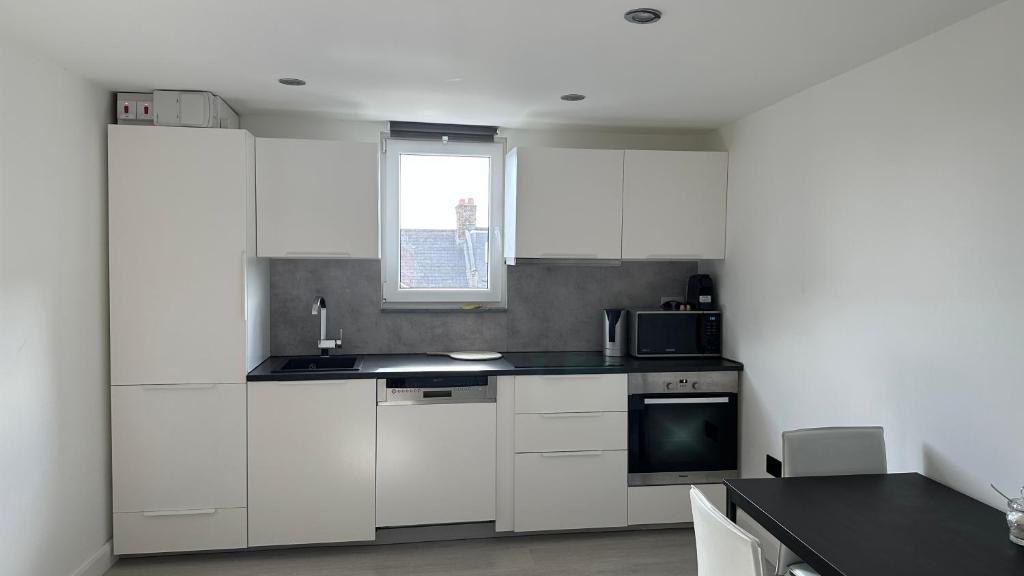 伦敦Stunning new 1 bedroom apartment的厨房配有白色橱柜和窗户。