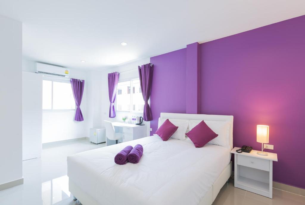 乔木提恩海滩诚之Z酒店的一间卧室设有紫色的墙壁和一张带紫色枕头的白色床。