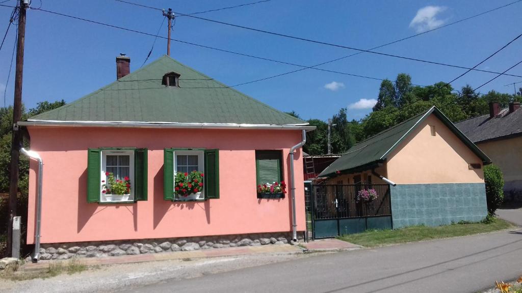 锡尔沃斯瓦里德Liána Vendégház的粉红色的房子,窗户上放着花盒