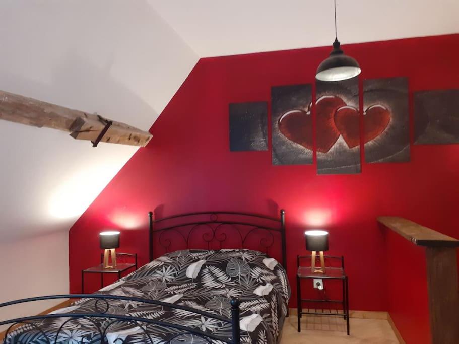 Verdelotstudio atypique et reposant的卧室的墙壁上设有红色的墙壁,墙上有两颗心