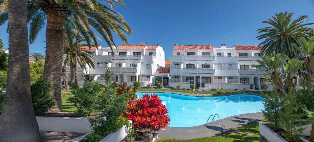 洛思坎加约斯洛斯罗萨雷斯公寓的一座白色的大建筑,设有游泳池和棕榈树