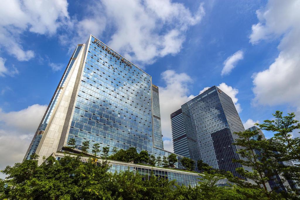 深圳深圳四季酒店的两座高大的玻璃建筑,前面有树木