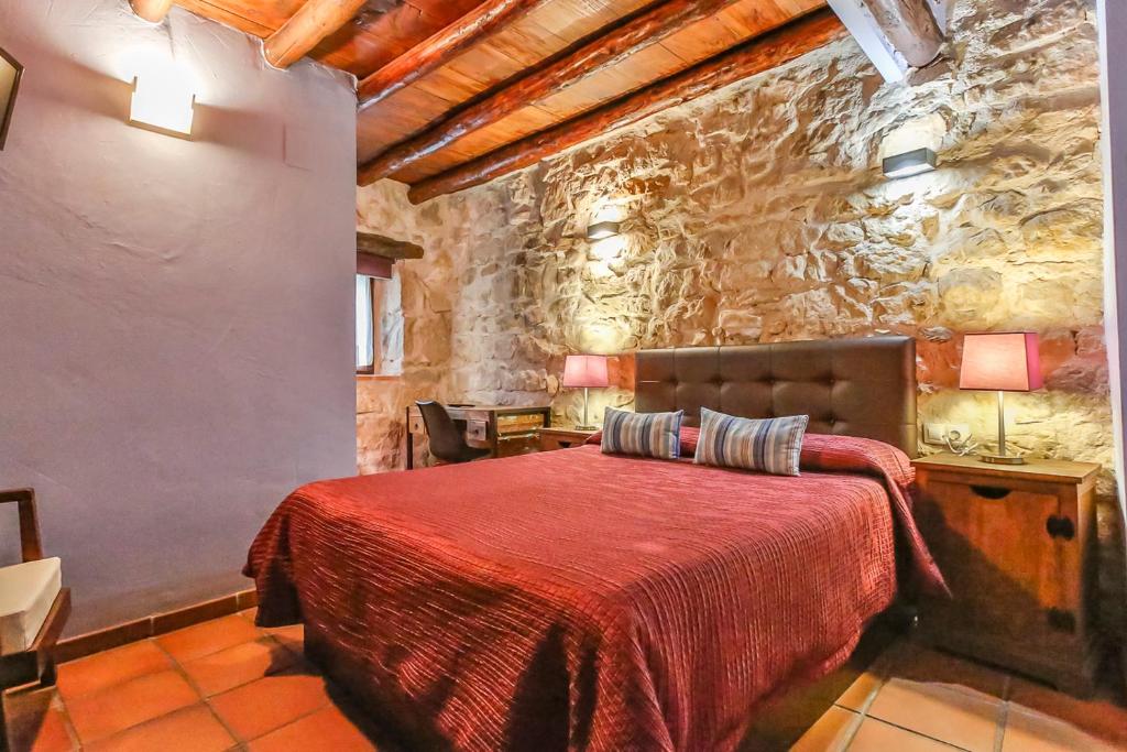 拉弗雷斯内达方达拉格拉查宾馆的一间石墙卧室,配有红色的床
