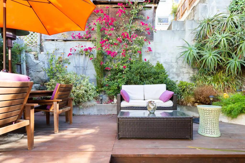 旧金山Beautiful Condo in Sun Drenched Garden的天井配有椅子和带雨伞的桌子