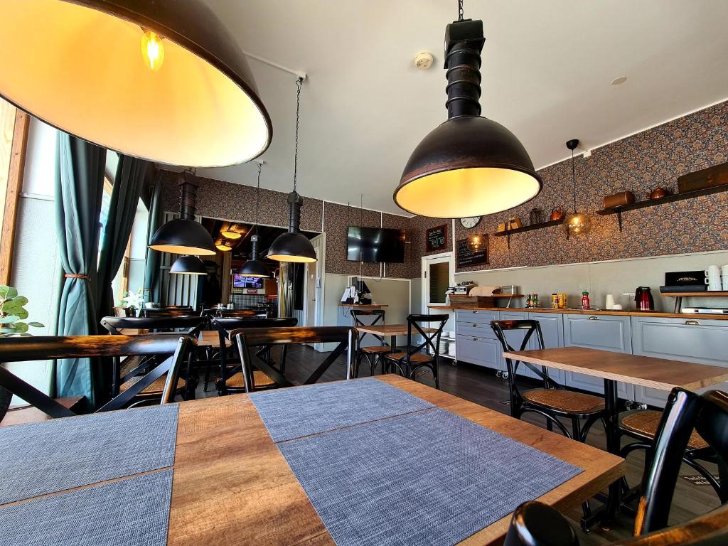 Dala-JärnaDala-Järna Hotell och Vandrarhem的餐厅设有木桌、椅子和吊灯