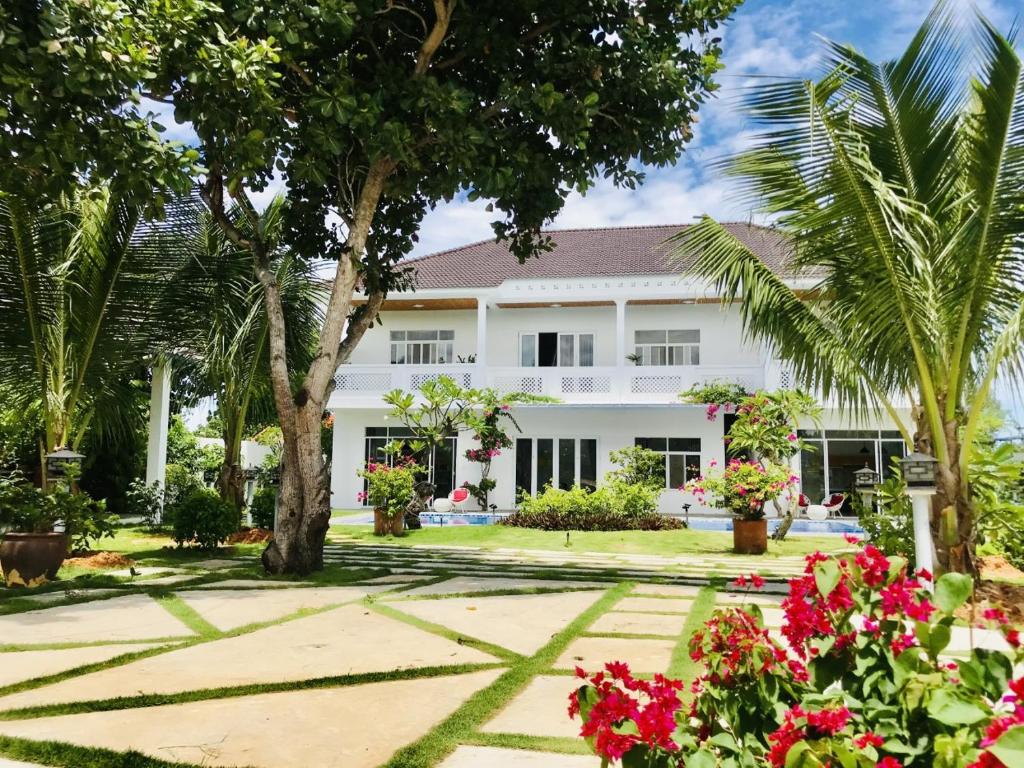 Ấp Thiện SơnCasa Vi Mia的棕榈树和鲜花的白色房子