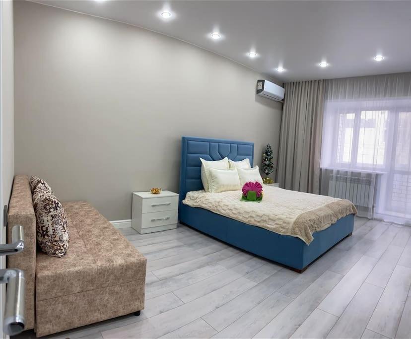库斯塔奈VIP апартаменты в центре города的一间卧室配有蓝色的床和沙发