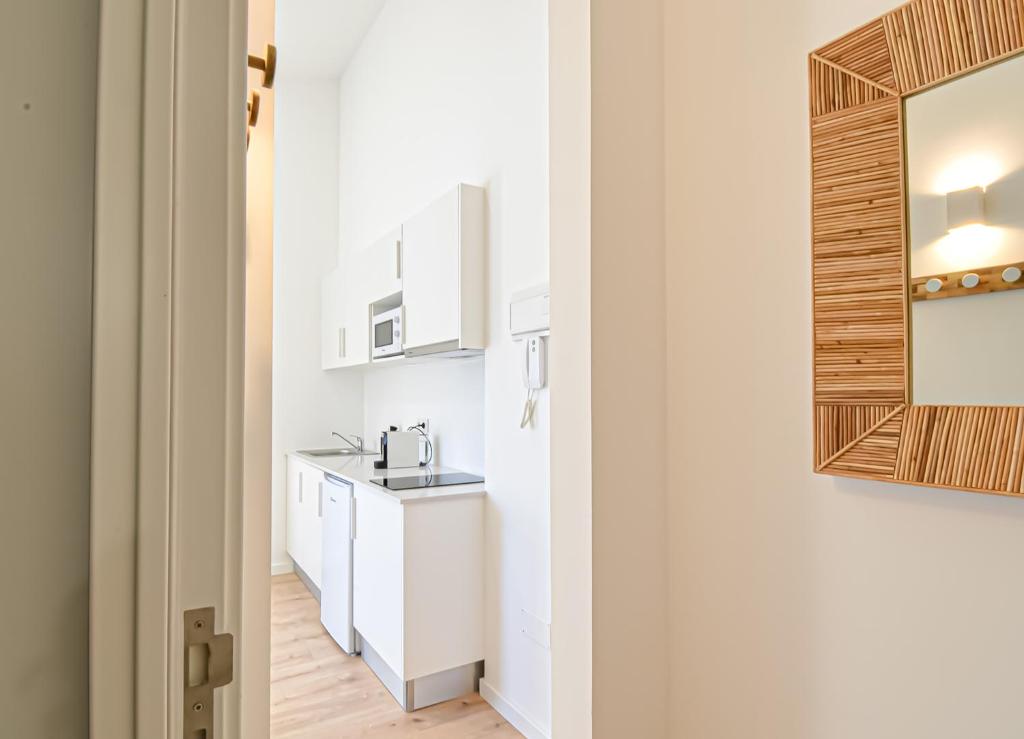 科英布拉LAA Studios的厨房配有白色橱柜、水槽和镜子