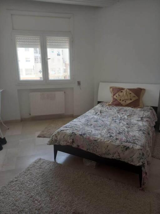 突尼斯Appartement plein Centre Urbain的一间卧室配有一张床、两个窗户和两块地毯
