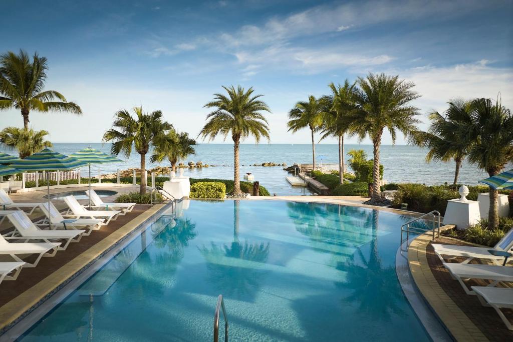马拉松Courtyard by Marriott Faro Blanco Resort的一座棕榈树和海洋的大型游泳池