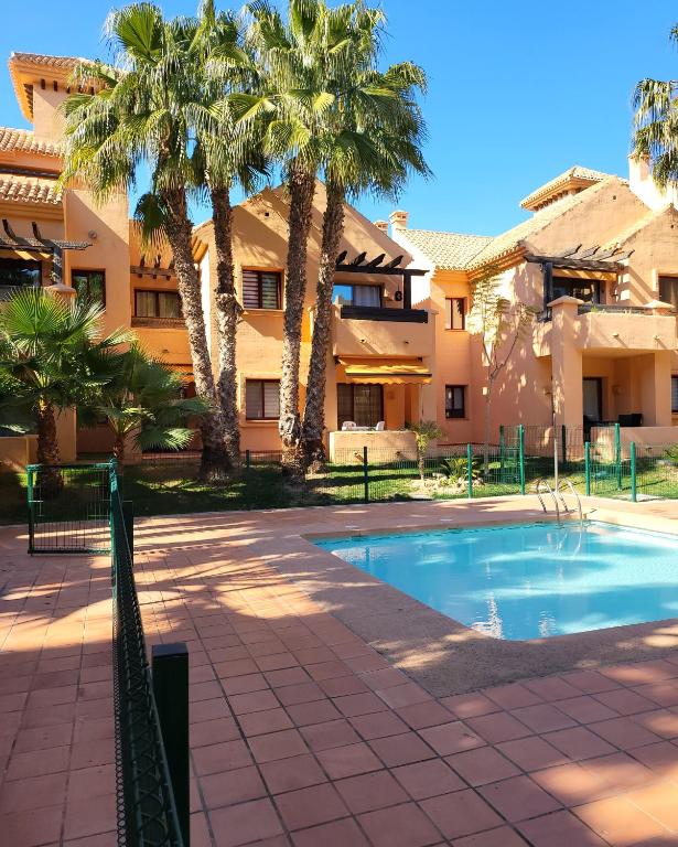 洛斯阿尔卡萨雷斯Geweldig Appartement in Los Alcázares direct aan de Boulevard的棕榈树建筑前的游泳池