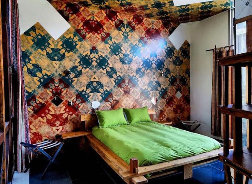 瓦尔帕莱索PazZHOtel的卧室在色彩缤纷的墙壁前设有一张绿色的床