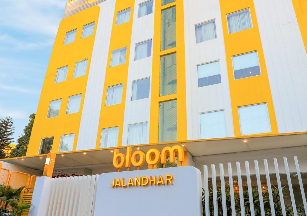 贾朗达尔Bloom Hotel - Jalandhar的黄色和白色的建筑,前面有标志