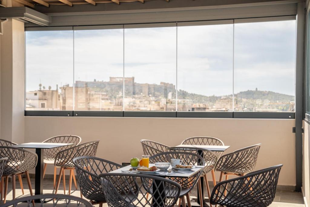 雅典Dunlin Hotel的餐厅设有桌椅和大窗户。