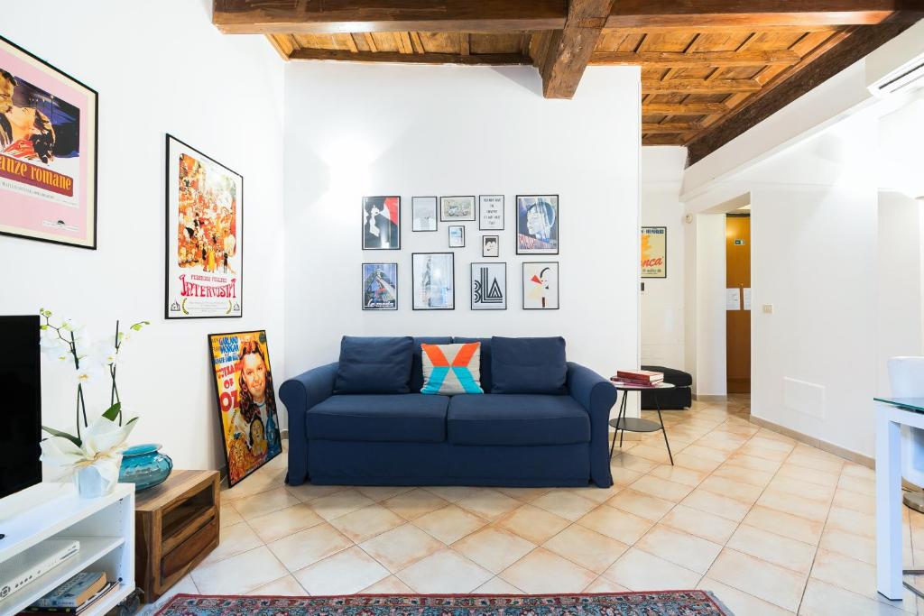 罗马Suites Campo de' Fiori - Zen Real Estate的客厅配有蓝色的沙发和墙上的照片