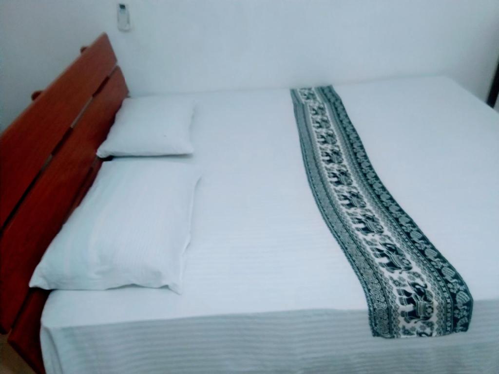 锡吉里亚Sigiriya Guest House Inamaluwa的白色的床,配有黑白色的棉被