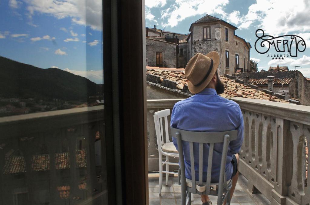 莫拉诺卡拉布罗Albergo Merùo的坐在阳台上的椅子上,从窗户望出去的人