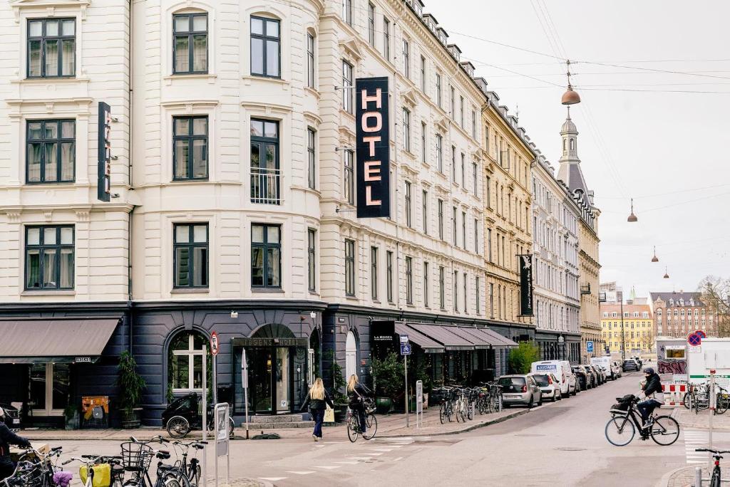 哥本哈根易卜生酒店的一条城市街道上的一座大型建筑,人们骑着自行车
