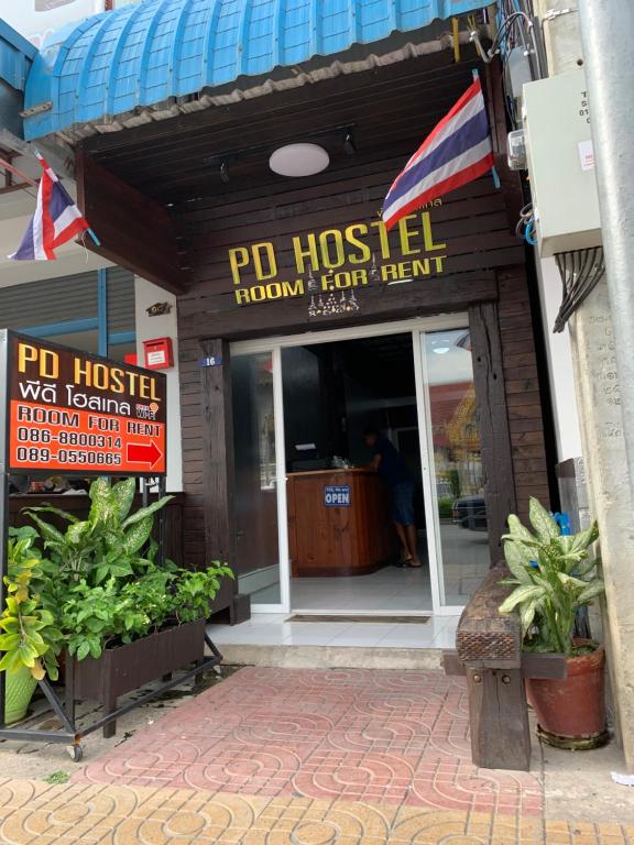 班敦孟PD Hostel的带有旅馆标志和植物的餐厅入口