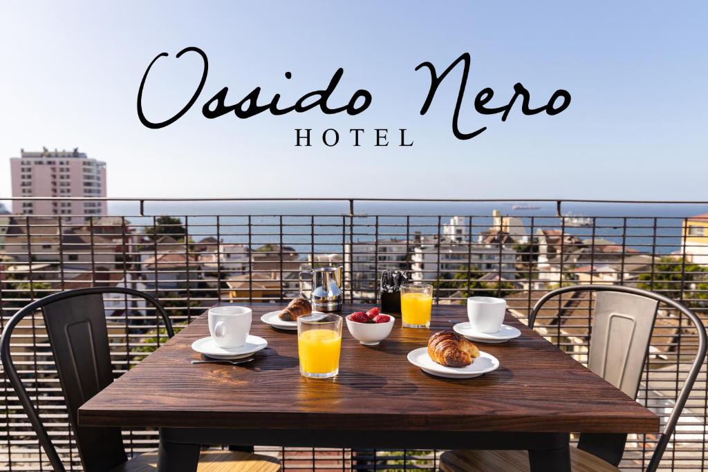 维纳德马Hotel Ossido Nero的阳台上配有一张带食品和饮料的木桌