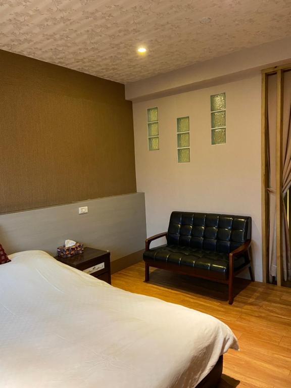 Ruifang橙橙民宿的一间卧室配有一张床和一张黑色皮沙发