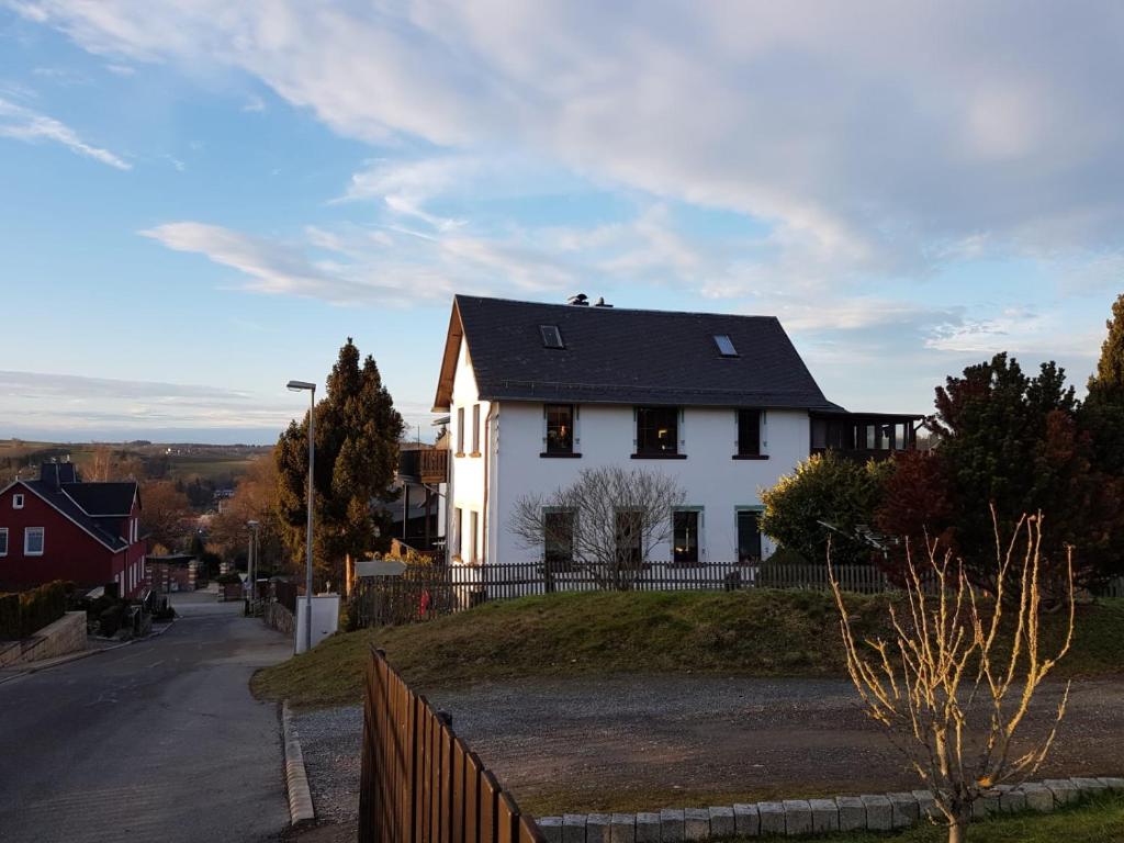 施内贝格Familienfreundliche Ferienwohnung Erzgebirge的山坡上白色的房子,屋顶黑色