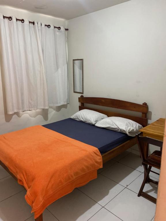 新弗里堡Pousada Serra Carioca Friburgo的一间卧室配有一张带橙色毯子的床和一张书桌