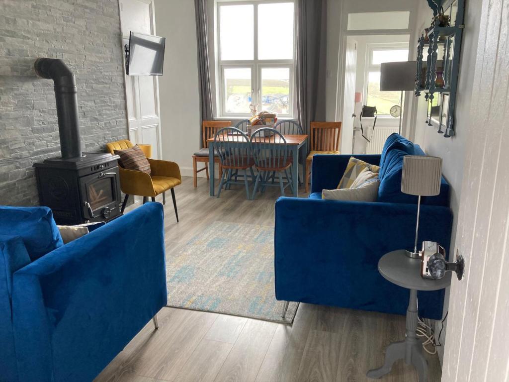贝尔马利特Glenhill - Newly renovated in a unique location的客厅配有2张蓝色沙发和1个燃木炉子