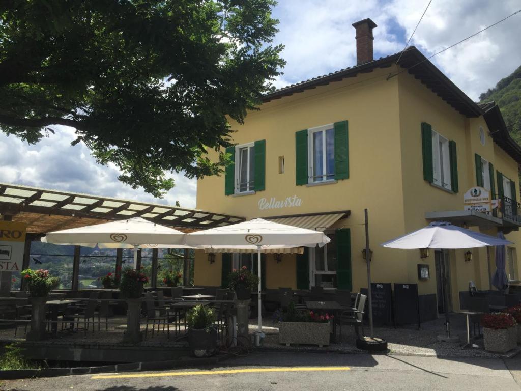 加维科利亚诺Hotel Bellavista Cavigliano的前面有桌子和伞的建筑