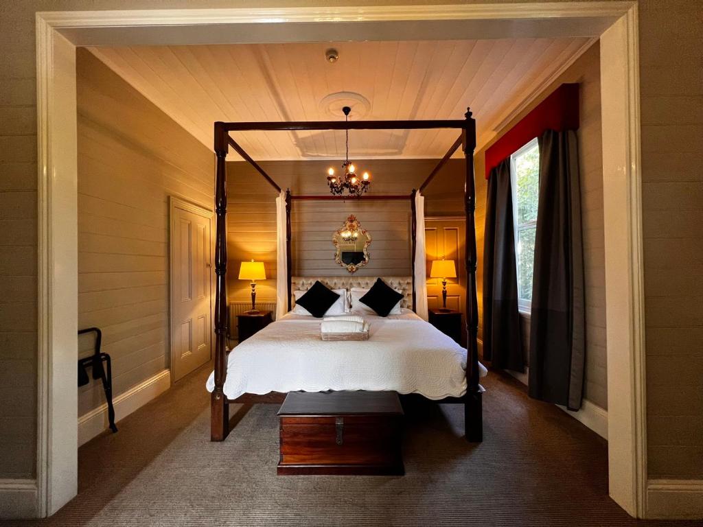 黑荒地The Boutique Hotel Blue Mountains的一间卧室配有一张天蓬床和吊灯。