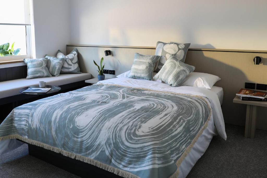 悉尼Beach Road Hotel的一间卧室配有一张大床,提供蓝白色的毯子