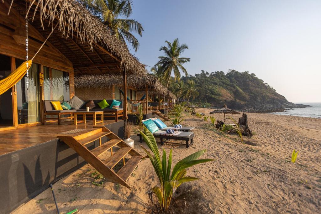 卡纳科纳Bamboo Yoga Retreat的海滩上的度假村,配有椅子和吊床