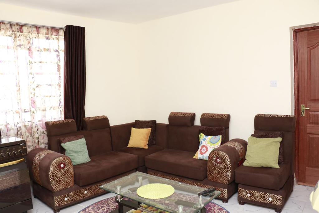 内罗毕Zanale Stays Furnished Apartment?的客厅配有棕色沙发和两把椅子