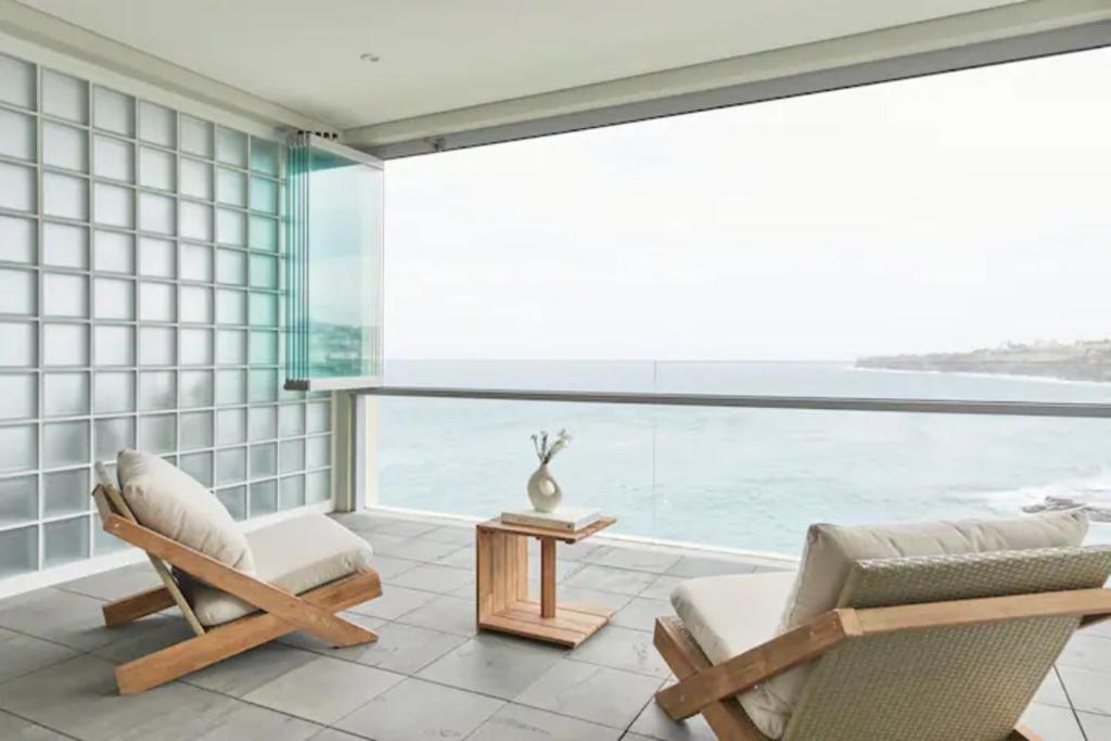 悉尼Oceanfront Tamarama Apartment: Best View in Sydney的客房设有两把椅子、一张桌子和大窗户