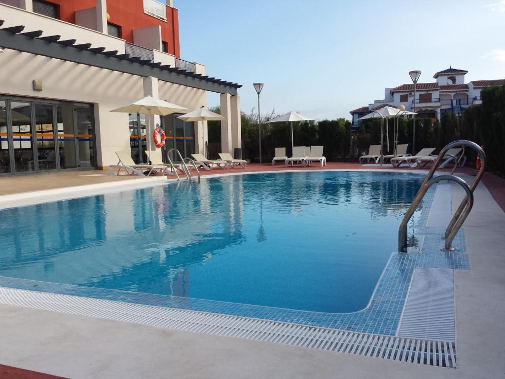 维拉Hotel Adaria Vera的一个带椅子和遮阳伞的大型游泳池