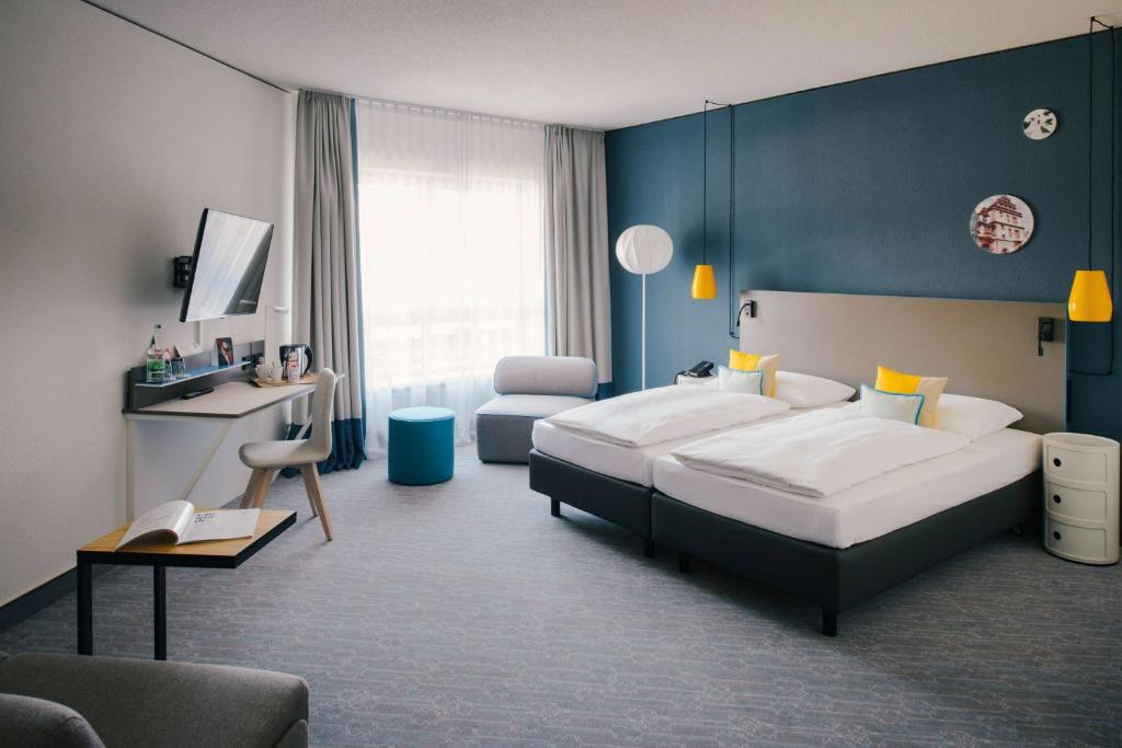 科堡Vienna House Easy by Wyndham Coburg的一间卧室设有一张大床和蓝色的墙壁