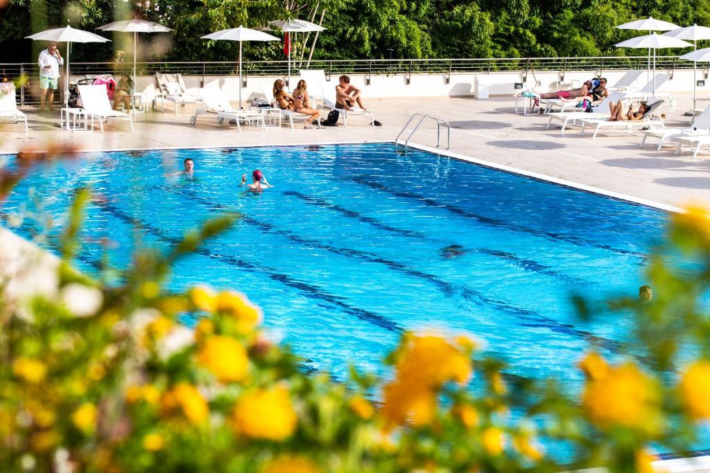 罗马Hotel Villa Pamphili Roma的游泳池,游泳池里有人坐在椅子和遮阳伞下