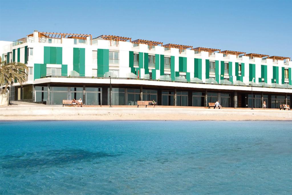 科拉雷侯Hotel LIVVO Corralejo Beach的一座大型建筑,旁边是绿色和白色的窗户