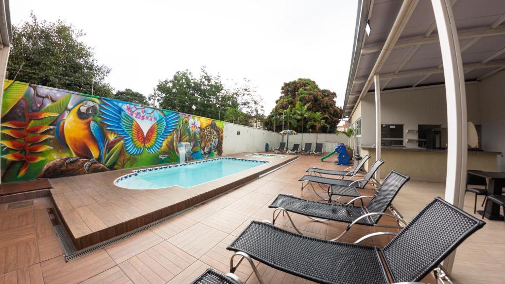 戈亚尼亚Allegro Hotel的一个带椅子的游泳池和一个带壁画的墙壁