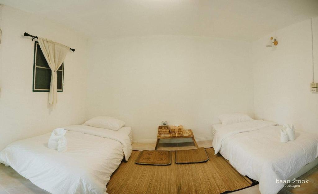 Ban MakokBaannok cottages Lamphun的白色墙壁客房中的两张单人床