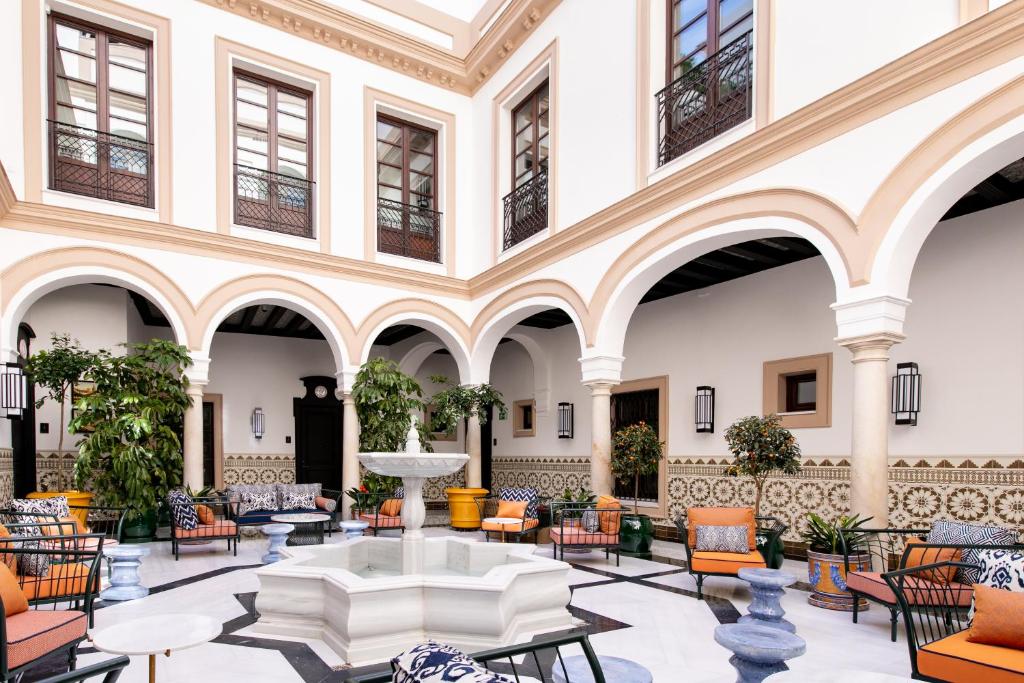 塞维利亚Hotel Casa Palacio Don Ramón的大堂设有喷泉、桌椅