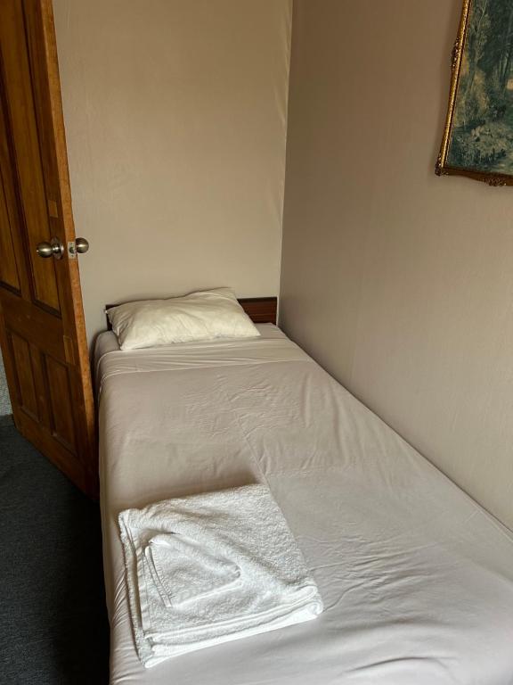 PahiatuaClub Hotel Pahiatua的一张带白色床单和枕头的小床