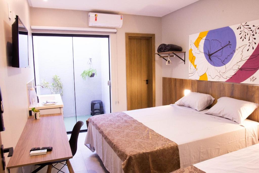 戈亚尼亚Fiori Suítes的一间卧室配有两张床、一张桌子和一台电视。
