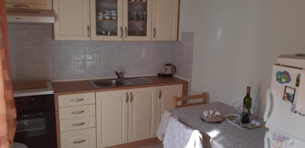 耶尔萨Apartman Bogdan的厨房配有白色橱柜、水槽和桌子