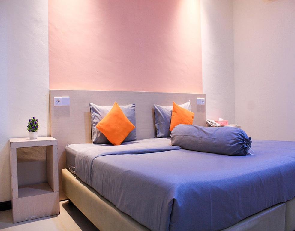 BagansinembahSuzuya Hotel Bagan Batu的一间卧室配有一张带蓝色床单和橙色枕头的床。